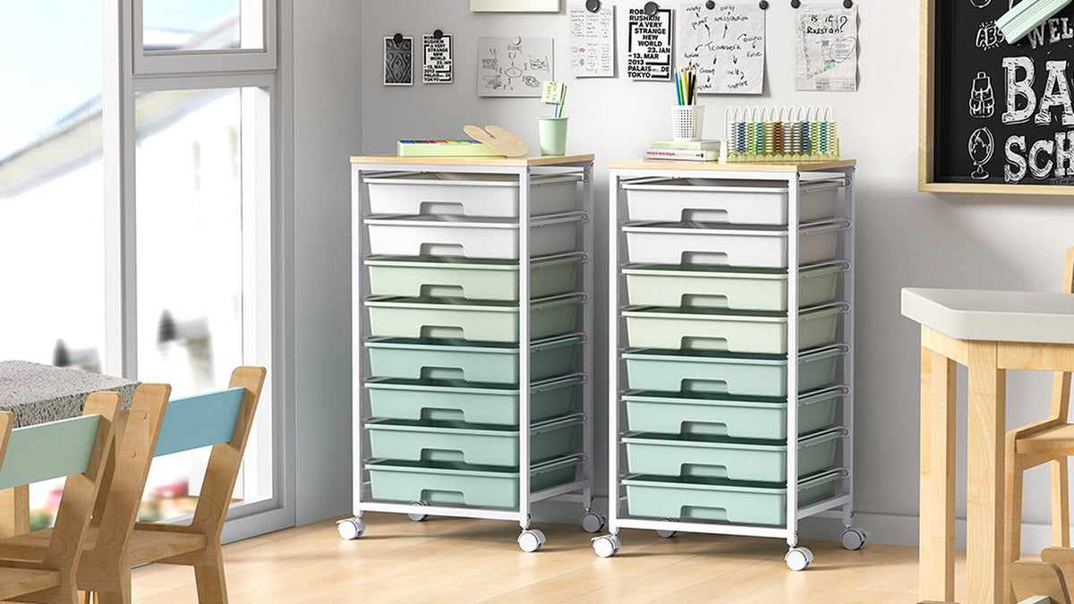 Two tall mint green rolling drawer carts in a classroom with a chalkboard and wooden table and chairs
